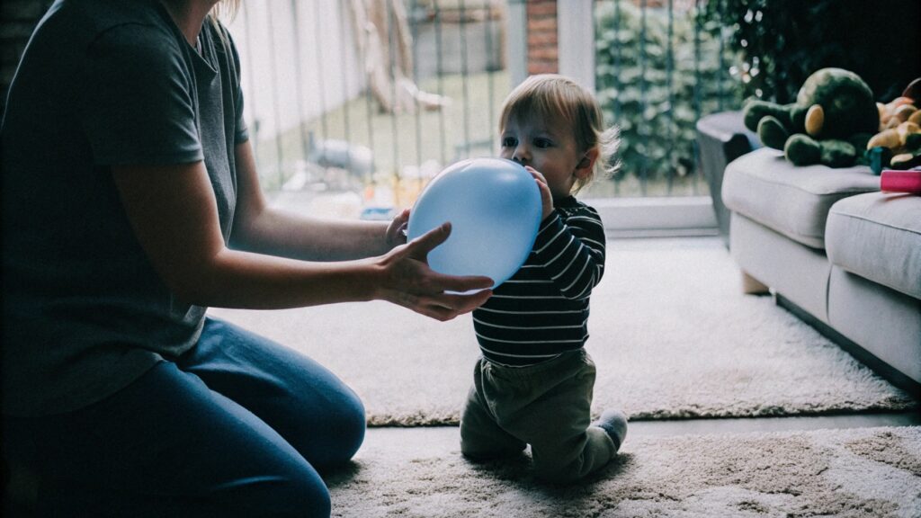 Adult supervising a child playing with a balloon