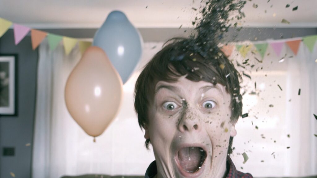 A person looking surprised as a balloon pops behind them