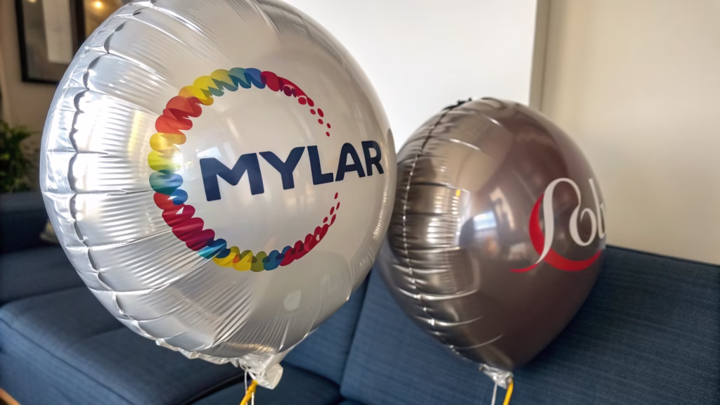 A perfectly printed custom logo on a Mylar balloon next to a stretched logo on a latex balloon
