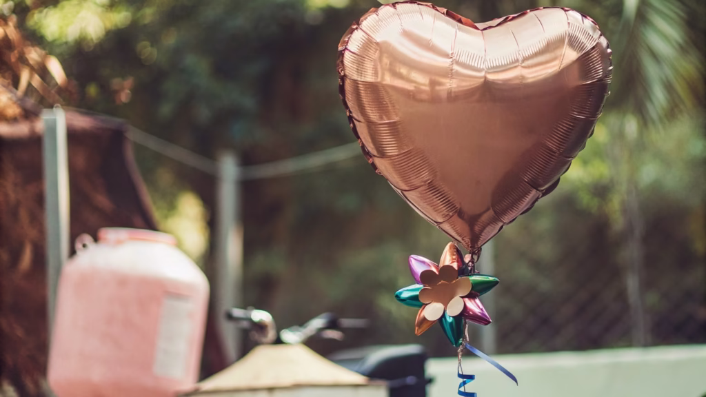 An image showing a single Mylar balloon tied with a decorative ribbon to a colorful balloon weight