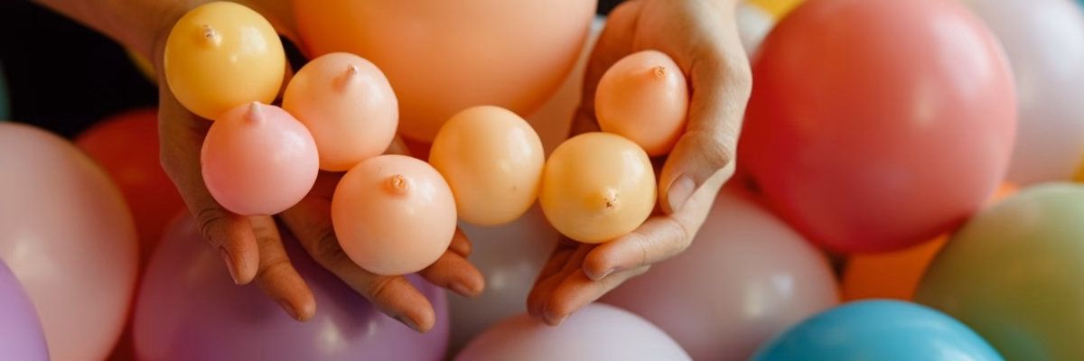Professional decorator using balloon sizer for consistent 5-inch balloon inflation