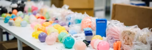 Wholesale latex balloon color samples and retail packs on a factory inspection table